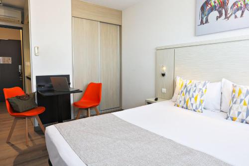 a bedroom with a bed and a desk with a laptop at Park Wilson Airport in Colomiers