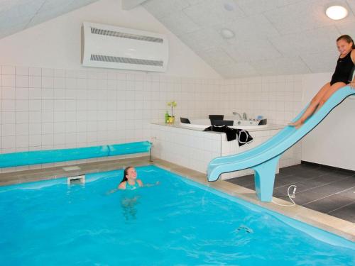 une femme glisse sur un toboggan dans une piscine dans l'établissement 14 person holiday home in L kken, à Løkken
