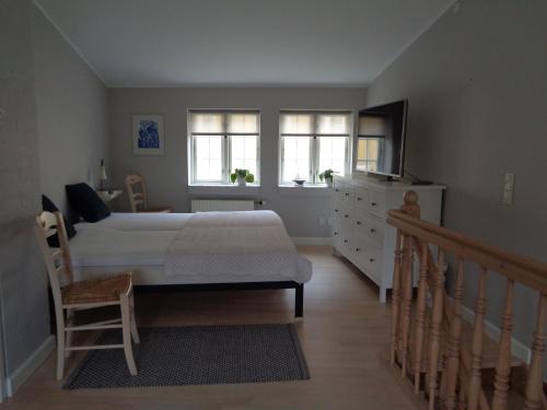 a bedroom with a bed and a dresser and windows at Dejligt lille byhus in Faaborg