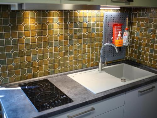 a kitchen with a sink and a tile wall at Ferienwohnung Auszeit in Bietigheim-Bissingen