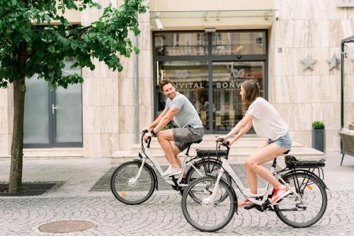 a man and a woman riding bikes down a street at Bonvital Hotel Hévíz Superior Adults Only in Hévíz