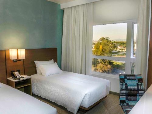 薩裘塞多皮海斯的住宿－ibis Styles Curitiba Aeroporto，酒店客房设有两张床和窗户。