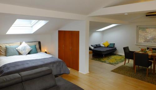 a bedroom with a bed and a couch and a table at Baker's Pond Loft Apartment in Velden am Wörthersee