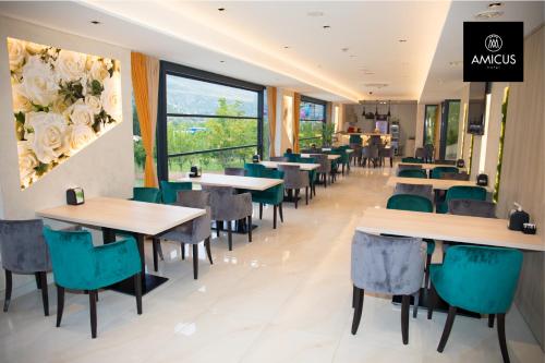a restaurant with tables and chairs and a large window at Hotel Amicus in Mostar