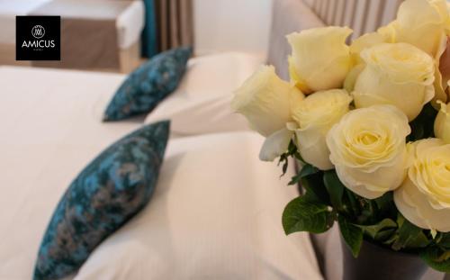 a vase of yellow roses sitting on a bed at Hotel Amicus in Mostar