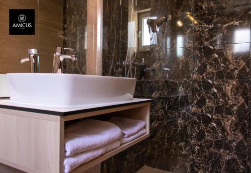 a bathroom with a sink and a black marble wall at Hotel Amicus in Mostar