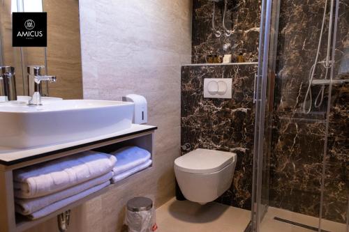 a bathroom with a sink and a toilet and a shower at Hotel Amicus in Mostar