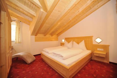- une chambre avec un lit et un plafond en bois dans l'établissement Gästehaus Kastenhof, à Sankt Johann im Pongau