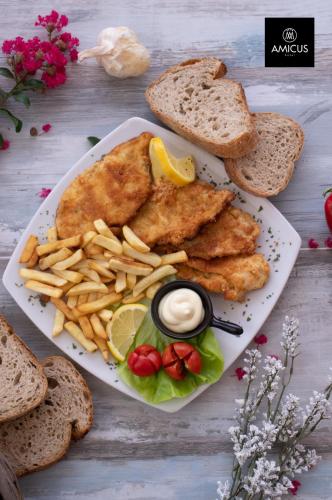 a plate of food with fish and french fries and bread at Hotel Amicus in Mostar