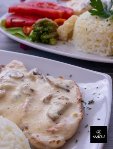 two plates of food with chicken and rice and broccoli at Hotel Amicus in Mostar
