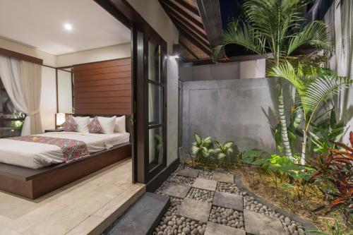 a bedroom with a bed and some plants at Villa Litera Seminyak Bali in Seminyak
