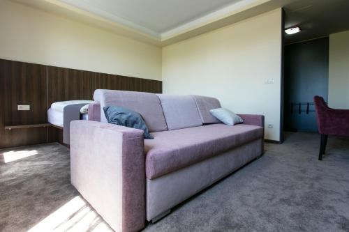 a purple couch in a room with a bed at New York Pension in Dunajská Streda