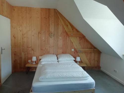 a bed in a room with wooden walls at Gîte de Granit Noir in Besse-et-Saint-Anastaise