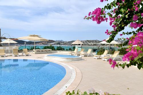 a swimming pool with lounge chairs and umbrellas at Royal Palm Residence in Bodrum City