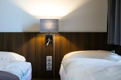 a hotel room with two beds and a light on the wall at New York Pension in Dunajská Streda