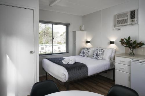 a small bedroom with a bed and a window at BIG4 Castlemaine Gardens in Castlemaine