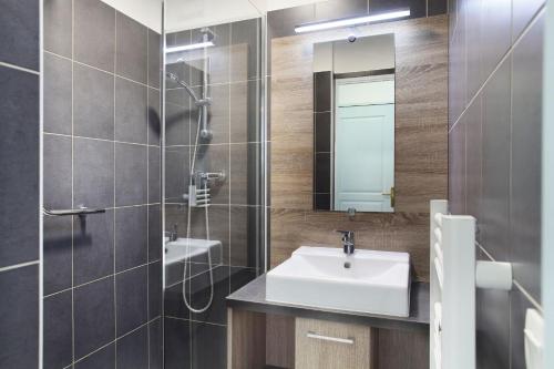 ein Bad mit einem Waschbecken, einer Dusche und einem Spiegel in der Unterkunft Résidence Odalys Domaine des Eucalyptus in Saint-Aygulf