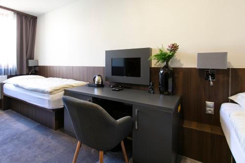 a hotel room with a desk with a television and a bed at New York Pension in Dunajská Streda
