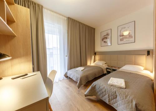 ein Hotelzimmer mit 2 Betten und einem Schreibtisch in der Unterkunft Wolska Residence I in Warschau
