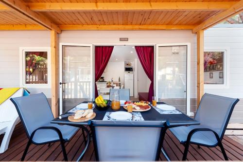 a dining table and chairs on a porch with a table and chairsktop at Mobile Homes Bi Village - Adriatic Kampovi in Fažana