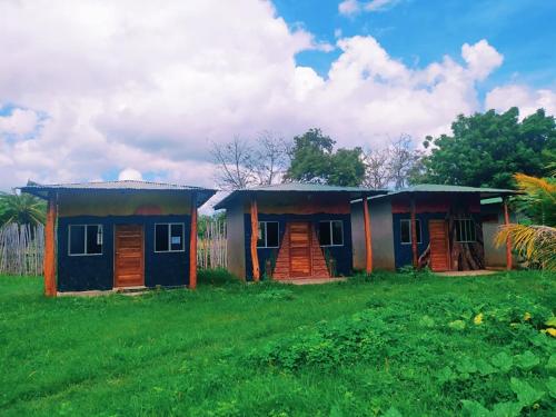 two small houses in a field with a green field at Ruamoko Hostel in Rivas