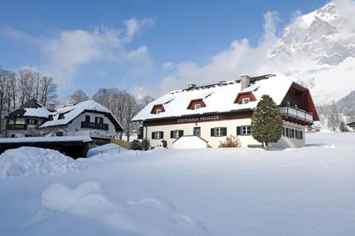 a house covered in snow with mountains in the background at Gästehaus Prugger by Schladmingurlaub in Ramsau am Dachstein