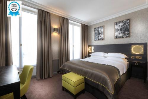 パリにあるヴァンドーム オペラ ホテルのベッド、デスク、窓が備わるホテルルームです。