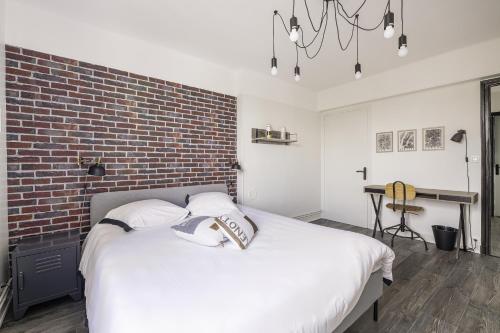- une chambre avec un lit blanc et un mur en briques dans l'établissement Cosy appartement neuf sur le port de plaisance de Caen, à Caen