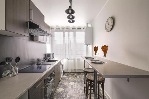 une cuisine avec un comptoir et une horloge au mur dans l'établissement Cosy appartement neuf sur le port de plaisance de Caen, à Caen