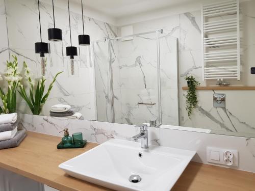 ein weißes Badezimmer mit einem Waschbecken und einem Spiegel in der Unterkunft Old Motława Mirror Apartment in Danzig