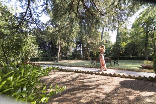 a woman in a dress standing in a park at Hotel Villa Quiete in Montecassiano
