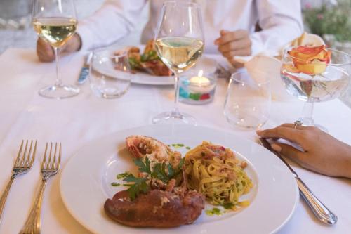 a table with a plate of food and glasses of wine at Hotel Villa Quiete in Montecassiano