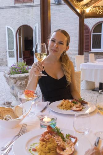 a woman sitting at a table with a glass of wine at Hotel Villa Quiete in Montecassiano