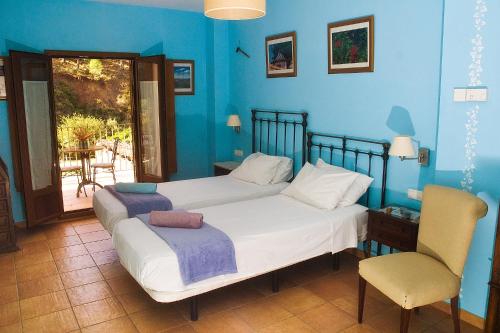 a blue bedroom with a bed and a chair at Posada San Marcos in Alájar