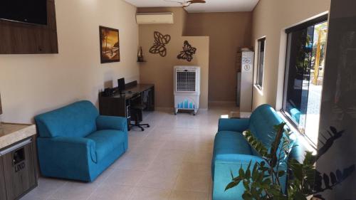 a living room with two blue chairs and a desk at Pousada Kaluanã in Olímpia