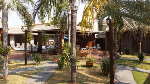 a resort with palm trees in front of a building at Pousada Kaluanã in Olímpia