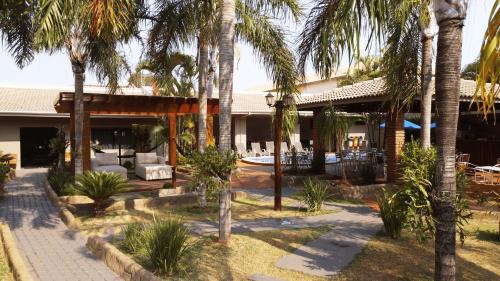 a resort with palm trees in the courtyard at Pousada Kaluanã in Olímpia