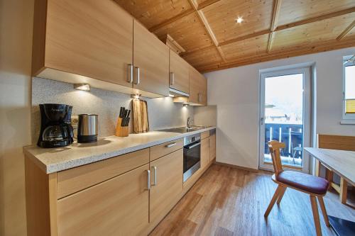 a kitchen with wooden cabinets and a table and a chair at Appartements Christine in Maishofen