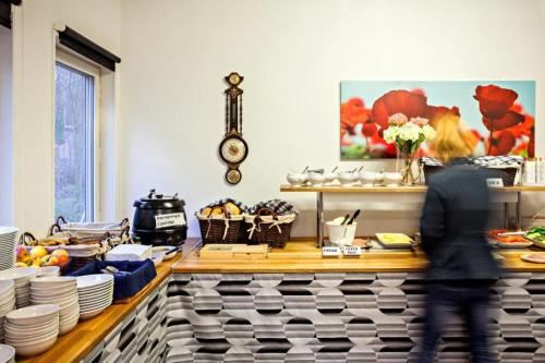 a woman walking in front of a counter with plates at Hotell Dialog in Stockholm