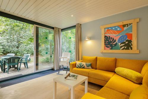 a living room with a yellow couch and a table at Center Parcs Heijderbos Limburg-Weeze in Heijen