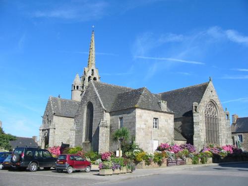 a church with cars parked in a parking lot at En Bretagne, villa de 2 à 8 pers , meublé de tourisme 3 étoiles nichée dans un écrin de verdure à 2500m de la plage in Ploumilliau