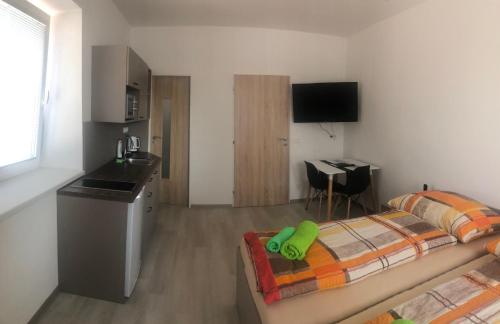 a bedroom with a bed and a kitchen with a desk at Apartmány U Stadionu in Šumperk