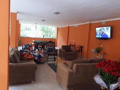 sala de estar con sofás y TV de pantalla plana. en Pousada Serraninhos, en Santa Leopoldina