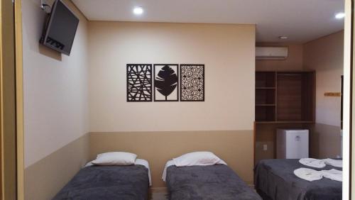 um quarto com duas camas e uma televisão na parede em Pousada Kaluanã em Olímpia