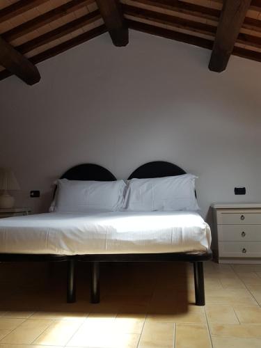 a bedroom with a white bed with a black headboard at Saturnia Tuscany Country House in Saturnia
