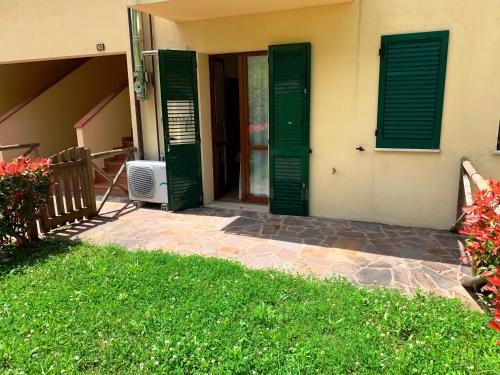 a door with green shutters on a house at Saturnia Tuscany Country House in Saturnia