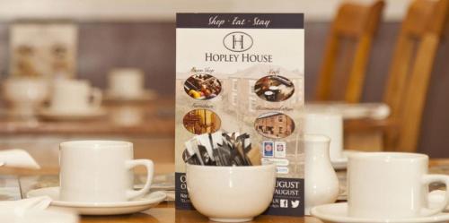 a table with white cups and saucers on a table at Hopley House in Middlewich
