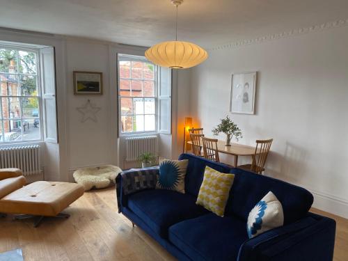 a living room with a blue couch and a table at Stunning Georgian Flat in The Heart of Midhurst Old Town in Midhurst
