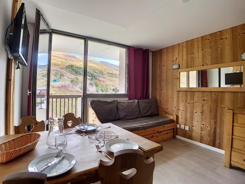 une salle à manger avec une table et une grande fenêtre dans l'établissement travelski home select - Résidence Médian by Travelski, aux Menuires