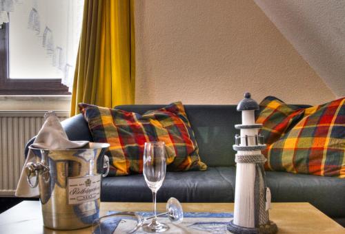 a living room with a couch and a table with a wine glass at Hotel & Restaurant Am Wasser in Breege